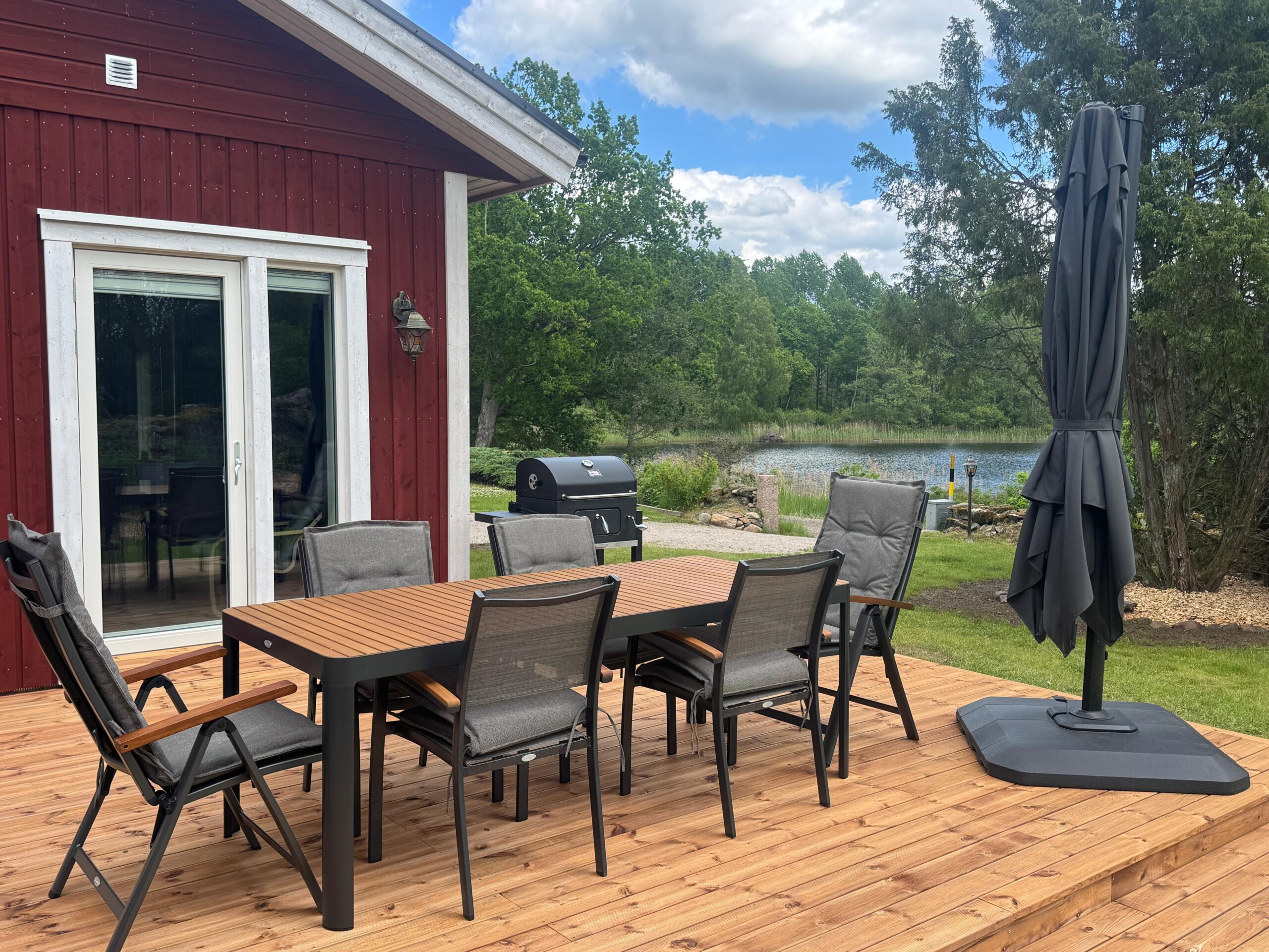 Designer-Terrasse mit Sonnenschirm und Grill, Seeblick